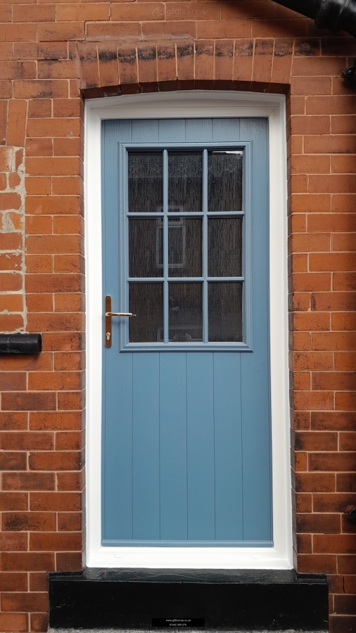 The Solidor Flint Beeston GB composite door showcases a rustic vertical plank style integrated with an elegant, small Georgian Bar (GB) glazed window